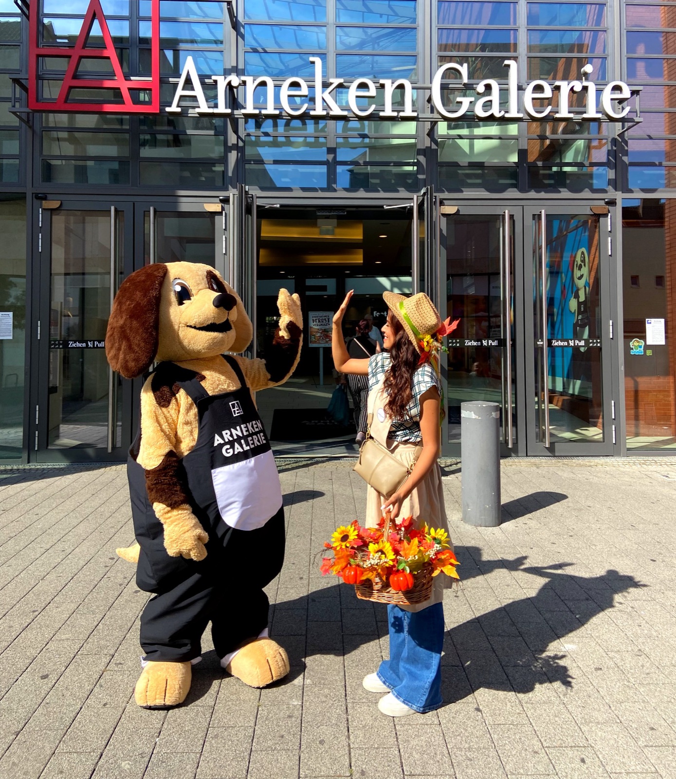 Arnie und seine herbstlich kostümierte Begleitung winken vor dem Eingang der Arneken Galerie