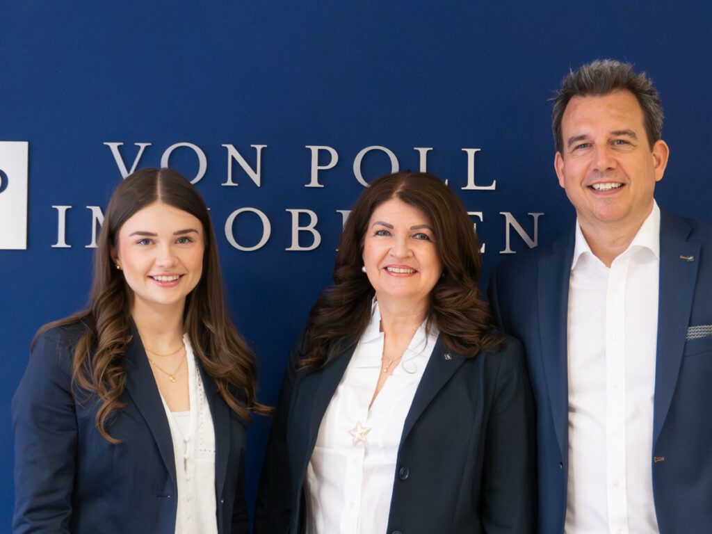 Das Team von VON POLL IMMOBILIEN Hameln vor der Logowand