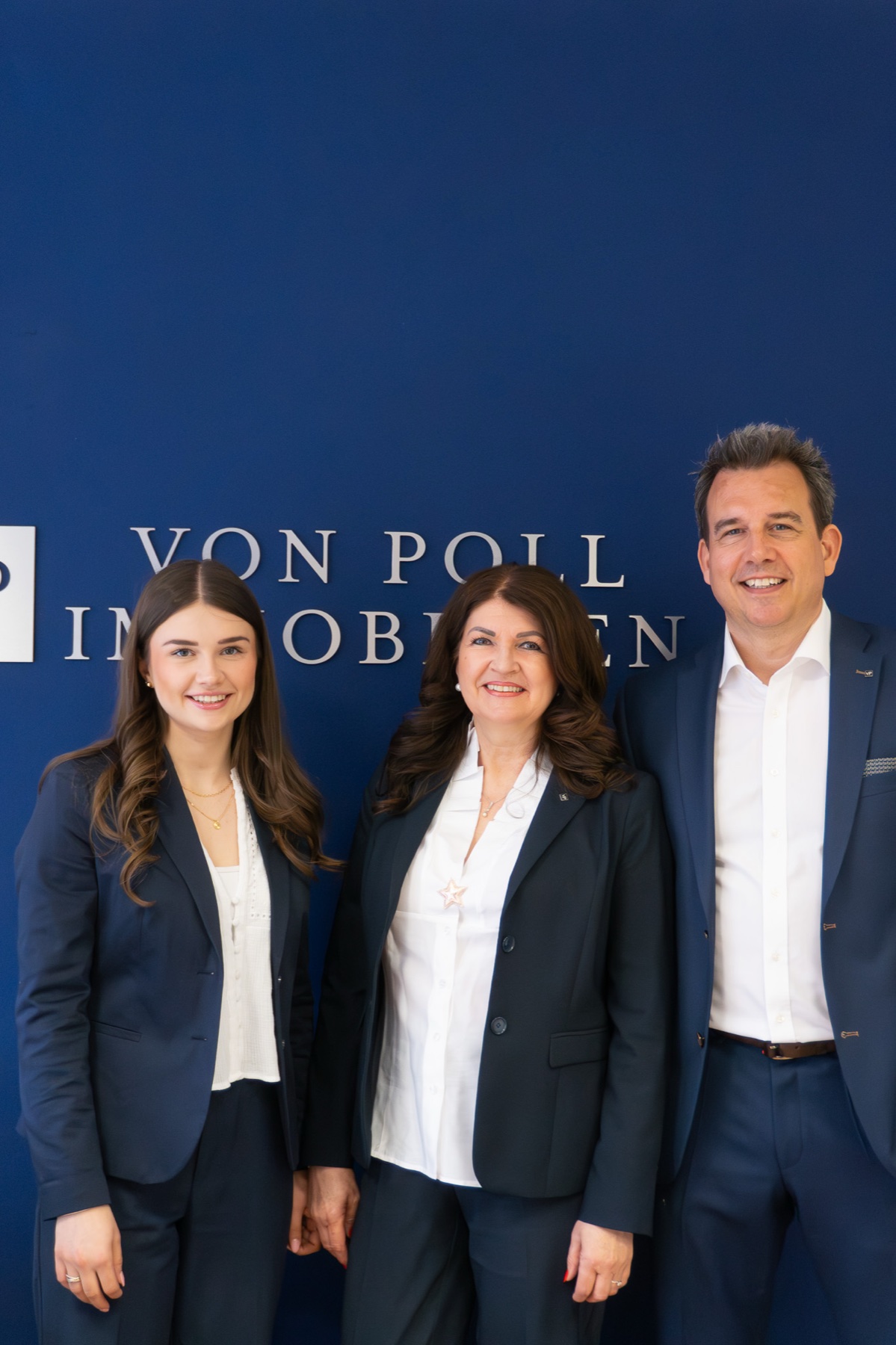 Das Team von VON POLL IMMOBILIEN Hameln vor der Logowand
